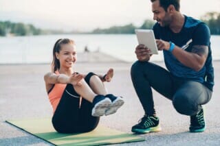 Hotel Atlantic Junge Frau macht Fitnessübungen auf einer Matte, während ein Trainer sie anleitet.