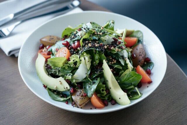 Bunter Salat mit frischem Gemüse, Granatapfelkernen und Nüssen in einer Schüssel.