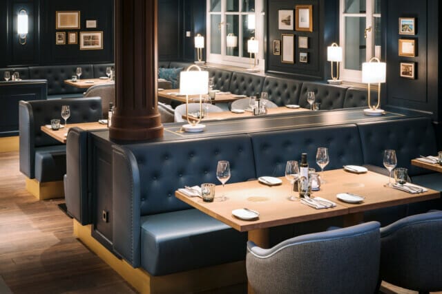 Elegantes Restaurantinterieur mit blauen Polsterbänken und stilvollen Holztischen.