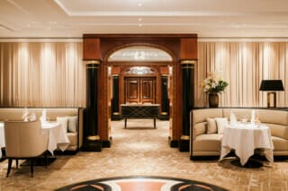 Elegantes Restaurantinterieur mit Tischen, gemütlichen Sitzgelegenheiten und stilvollem Dekor.