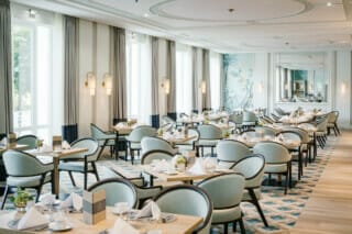 Elegantes Restaurant mit stilvollen Tischen, Stühlen und viel natürlichem Licht.