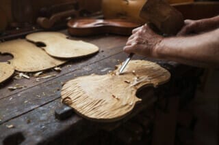 Hotel Atlantic Handicraft process of violin making with wood and tools on a workbench.