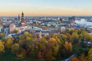 Hotel Atlantic Panorama von Hamburg mit bunten Herbstbäumen und der St. Michaelis-Kirche im Hintergrund.