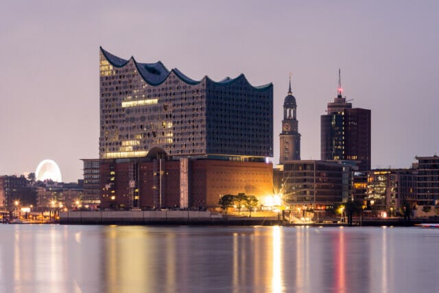 Elbphilharmonie Hamburg with a view of the harbour at night, illuminated by city lights.