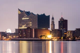 Hotel Atlantic Hamburgs Elbphilharmonie bei Nacht, umgeben von modernen Gebäuden und dem Hafen.
