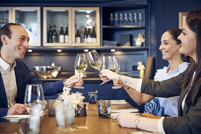 Freunde stoßen in einem eleganten Restaurant mit Weißwein an und genießen die gemeinsame Zeit.