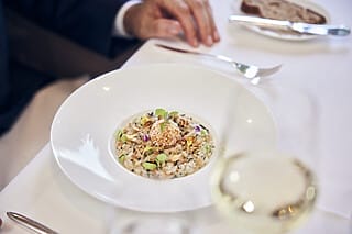Gourmetgericht mit Reis, Gemüse, Nüssen und einer dekorativen Perle, serviert im Restaurant.