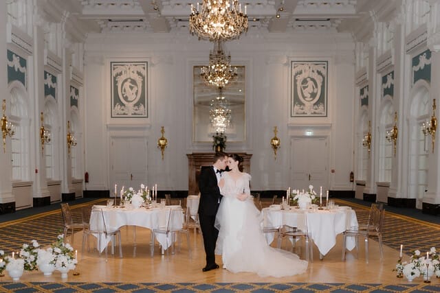 Brautpaar in festlichem Saal mit eleganter Dekoration und Kerzen auf den Tischen.